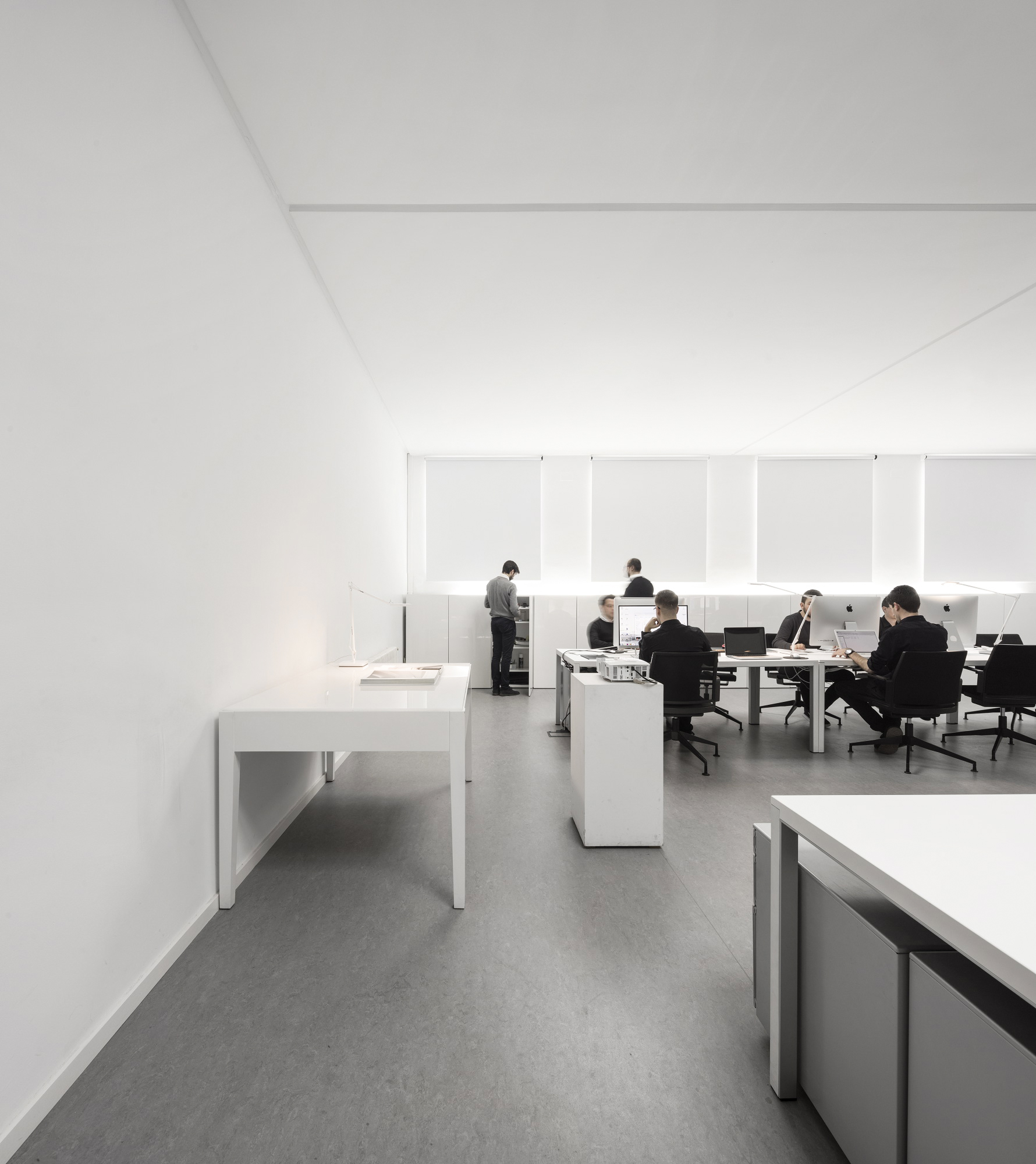 Estudio de diseño minimalista con mesas blancas y equipo trabajando